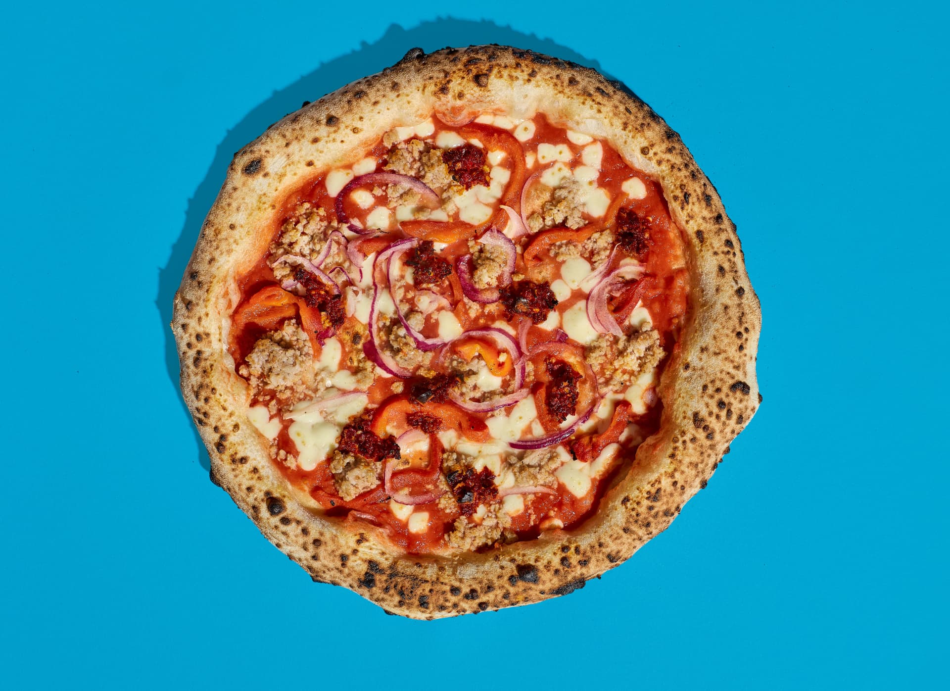 A Bona sourdough pizza with sausage, red onion and peppers